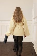 Person wearing a beige coat in an elegant interior setting