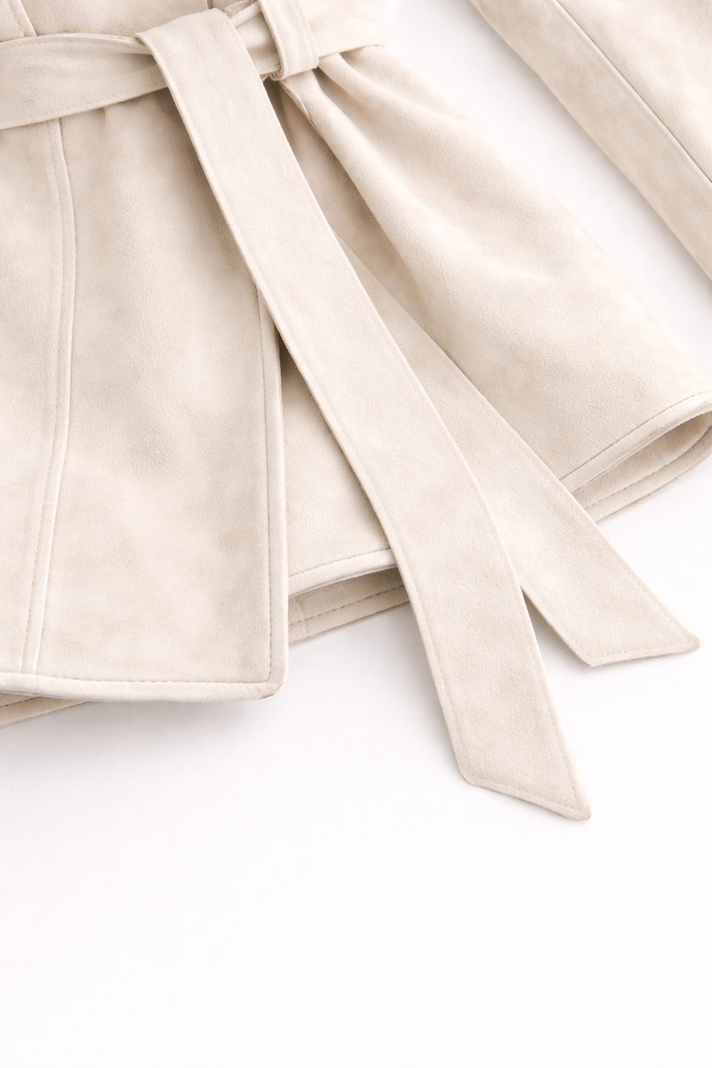 Close-up of a beige trench coat with a belt on a white background